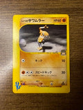 Japanese Hitmonlee Pokémon card with a soccer-themed illustration, yellow border, and VS series logo. Front angle 2.