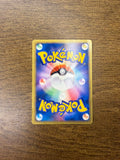 Pokémon card back placed on wood, featuring Poké Ball design with swirling colors and golden border. Back angle 2.