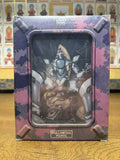 A photograph of the back of the Full Metal Panic! Mission 5 limited edition DVD box set on a wooden surface. The shrink-wrapped box displays the mecha illustration through the rear window, with a background of decorative cards visible behind the package.