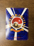Back of a Japanese Pocket Monsters card placed on wood, showing a Poké Ball with radiating beams and “CARD GAME” ribbon. Includes 1996 copyright info from Nintendo, Game Freak, and Creatures Inc.