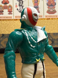 Close-up view of the Naval Commander Bosgun sofubi figure from Kamen Rider Black RX (1988), showing a stylized humanoid character with a full head mask in red, white, and green. The mask features sculpted eye holes and ear coverings. The figure wears a glittery green jacket with sculpted folds and buttons, paired with white pants featuring black vertical stripes. The pose is static with arms slightly bent downward, highlighting the retro tokusatsu villain design.