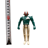 Naval Commander Bosgun sofubi figure from Kamen Rider Black RX (1988), standing upright next to a vertical measuring tape showing a height of approximately 10 cm. The figure wears a green top, white pants with black vertical stripes, and a red-and-white skull-like mask. The static pose and scale reference emphasize its compact size and collectible nature.