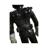 Rear view of the black-suited Kamen Rider Stronger figure with white gloves and a sculpted muscular back. Molded Japanese copyright text is visible: “© 石森プロ 毎日放送 東映,” confirming licensing by Ishimori Productions, Mainichi Broadcasting System, and Toei. The figure wears a belt and has detailed shoulder sculpting.