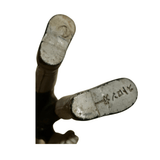 Close-up view of the underside of a vintage Popy 1975 Sofubi Kamen Rider Stronger figure’s feet. The left foot bears a molded stamp reading “X RAY” with an adjacent symbol, possibly a manufacturer’s mark. The right foot has a circular indentation, less legible but likely part of the original production mold. The surface is metallic and slightly worn, indicating age and authenticity.