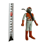 Full-body view of the Kamen Rider X figure standing beside a vertical measuring tape, showing a height of approximately 10.1 cm. The figure wears a light blue and red costume with a black scarf and red compound-eye helmet. The belt is detailed with a circular emblem. Measuring tape markings include “KSP,” “JIS,” and “55.5m.”