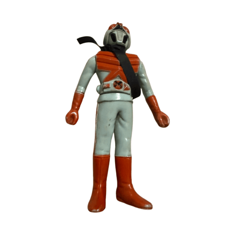 Front-facing view of the Kamen Rider X figure in a light blue suit with red gloves, boots, and chest armor. A black scarf crosses the chest and wraps around the neck. The helmet has a vented faceplate and red accents. The belt features a circular red and black emblem, and the figure stands on a marble-like surface.