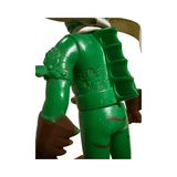 Rear view of the Popy Vintage Sofubi Kamen Rider Amazon figure, showing green torso, dark brown gloves, and a segmented spine-like sculpt on the back. A white scarf wraps around the neck. Embossed Japanese text reads “石森プロ 毎日放送 東映,” indicating official licensing from Ishinomori Productions, Mainichi Broadcasting, and Toei Company. The figure’s detailing and color scheme confirm its rare dark brown limb variant.