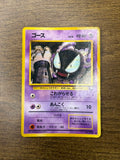 Japanese Gastly (ゴース) Pokémon card placed on a wooden surface, showing Gastly floating in front of a spooky tower. Features 40 HP, Level 13, Psychic-type purple border, two attacks—“こわがらせる” and “あんこく”—and card number No.092. Illustrated by Masako Yamashita.