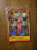 "Ultraman trading card with holographic geometric starburst background. Shows Mother of Ultra in a red and silver suit with glowing yellow eyes and a crest on her head. Chinese text notes her healing powers and her role as the mother of Taro. Card is encased in a plastic sleeve on a wooden surface."