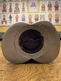 Close-up view of the underside of the Ultraman Gaia piggy bank, showing a butterfly-shaped or bowtie-like base with a central black circular component, likely a coin release stopper. Surrounding the stopper is engraved text reading “©1998 TSUBURAYA PROD. MBS,” confirming the item’s official licensing by Tsuburaya Productions and Mainichi Broadcasting System. The molded plastic base is metallic or glossy, providing authentication details crucial for collectors.