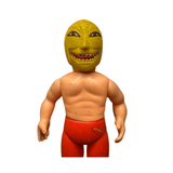 Frontal close-up of the Golden Mask figure featuring a bright yellow mask with wide eyes, sharp teeth, and exaggerated facial features. The figure has a muscular torso, red pants, and brown boots. The plastic surface shows scuffs and wear, particularly on the arms and legs, indicating age and handling.