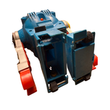 Vintage toy robot with a blue plastic body, silver arms, red feet, and yellow shoulder joints. The robot has a boxy torso with rivet-like details, vent patterns, and a face panel featuring two circular 'eyes' and a grill-like 'mouth.' The design reflects retro-futuristic aesthetics from mid-20th-century robotics."