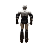 Complete rear view of the Shadowmoon sofubi figure from Kamen Rider Black (1988), featuring a metallic silver and black color scheme. The figure stands upright with clenched fists, wearing a helmet with dual antennae and sculpted armor plating across the shoulders, arms, and legs. The design reflects the biomechanical aesthetic of the character, emphasizing its villainous presence and collectible appeal.