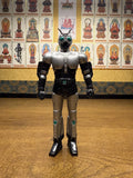 Frontal view of the Shadowmoon sofubi figure from Kamen Rider Black (1988), showcasing its iconic silver armor with black accents, riveted chest plating, and shoulder pads. The helmet features green compound eyes and twin antennae, while the belt displays a green circular emblem at the center. The figure’s upright pose and detailed sculpting capture the character’s cyborg-insect hybrid design, making it a standout piece for tokusatsu collectors.