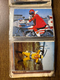 Two vintage Japanese tokusatsu trading cards stored in a plastic sleeve. The left card shows a blue-suited superhero aiming a bow at a villain on a staircase. The right card features the same hero wielding a weapon against a brightly colored villain with a sun-like face and yellow cape. Both cards include elaborate costumes and dramatic action poses typical of 1970s–80s Himitsu Sentai Goranger scenes. Copyright text “©石森プロ・NET・東映” is visible, confirming official production origins.