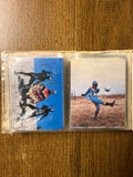 Fold-out photo album page featuring vertically arranged vintage cards from Japanese kaiju films and tokusatsu shows. The top cards depict monster battles including Godzilla, Mechagodzilla, and possibly Anguirus. The bottom card features Ultraman in a heroic pose. Each card includes Japanese text, and the layout suggests a curated collection of Showa-era monster and hero scenes, blending Godzilla and Ultraman franchises.
