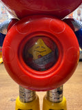 Close-up of the Batten Robomaru GB-94 toy robot’s head and upper torso. The figure has a circular red helmet with a blue faceplate featuring large cartoon-style eyes with white pupils and black outlines. The arms are blue with silver joints, and a yellow element is partially visible on the right side. The design is playful and expressive, reflecting the character’s animated personality and child-friendly aesthetic.