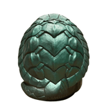 "Green sculpted object resembling a dragon egg, featuring a scale-like texture with symmetrical, angular segments. The surface mimics reptilian scales, and the egg has a rounded, solid form, likely made of resin or plastic. The design evokes fantasy themes and is suitable as a decorative or collectible item."