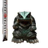 "Small figurine of Gamera, the kaiju turtle monster, shown next to a vertical measuring tape indicating a height of approximately 10 cm. The creature has a fierce expression with sharp teeth and tusks, a shell, and clawed limbs. The measuring tape displays numbers from 2 to 11, with '10' highlighted in red."